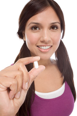 Young Latina woman showing white medication tablet